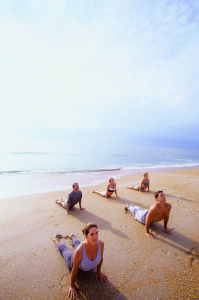 Group of people performing yoga on the beach